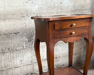 This lot features a Louis XV-style carved wooden nightstand with two drawers and cabriole legs in very good condition. This nightstand measures, 27.5” H x 17.5” W x 12.5” D.
