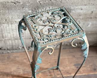 This lot features a vintage verdigris metal plant stand in good condition that measures, 25” H x 12.5” W x 12.5” D.
