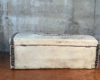 This lot features an antique trunk, most likely an immigrant trunk circa 1890s. The trunk is made of wood and animal hide with a lined paper interior. This trunk measures, 8” H x 21” W x 10.5” D.
