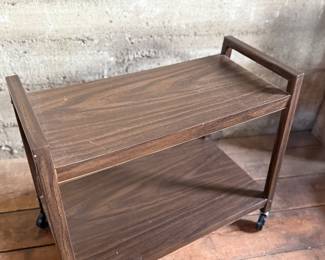 This lot features a vintage mid-century style cart on casters and measures, 24” H x 28.5” W x 13” D.
