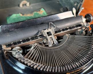 This lot features an antique Remington portable typewriter with a four-bank QWERTY keyboard, a folding type bar mechanism that raises the type bars for typing and lowers them for storage, making the machine compact, and housed in a carrying case. These typewriters were among the earliest and most successful portable models, first introduced in 1920.
