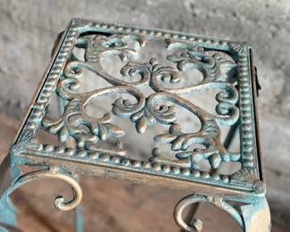 This lot features a vintage verdigris metal plant stand in good condition that measures, 25” H x 12.5” W x 12.5” D.
