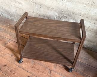 This lot features a vintage mid-century style cart on casters and measures, 24” H x 28.5” W x 13” D.
