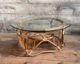 This lot features a vintage bamboo and rattan coffee table with a glass top, circa 1970s. In good overall condition and measures, 15” H x 30” W x 30” D.
