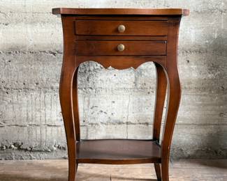 This lot features a Louis XV-style carved wooden nightstand with two drawers and cabriole legs in very good condition. This nightstand measures, 27.5” H x 17.5” W x 12.5” D.
