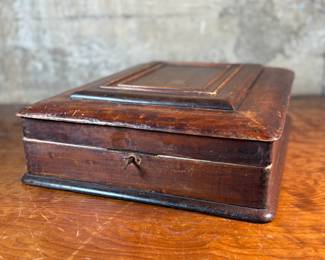 This lot features what appears to be a Victorian writing slope or lap desk. Locks and comes with the original skeleton key, with beautiful patina throughout. Please note, there is no "slope" and has a flat box surface inside. This stunning piece measures, 5” H x 14.5” W x 17.5” D.

