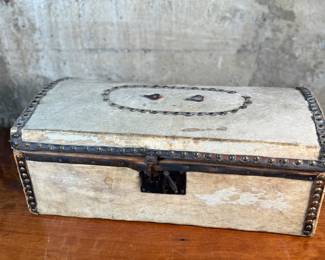 This lot features an antique trunk, most likely an immigrant trunk circa 1890s. The trunk is made of wood and animal hide with a lined paper interior. This trunk measures, 8” H x 21” W x 10.5” D.
