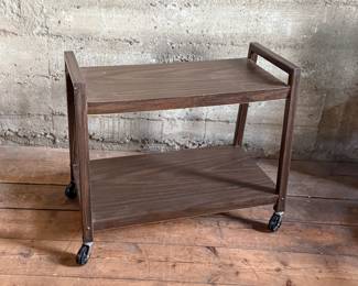 This lot features a vintage mid-century style cart on casters and measures, 24” H x 28.5” W x 13” D.
