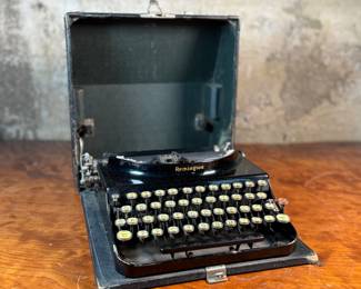 This lot features an antique Remington portable typewriter with a four-bank QWERTY keyboard, a folding type bar mechanism that raises the type bars for typing and lowers them for storage, making the machine compact, and housed in a carrying case. These typewriters were among the earliest and most successful portable models, first introduced in 1920.
