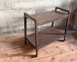 This lot features a vintage mid-century style cart on casters and measures, 24” H x 28.5” W x 13” D.
