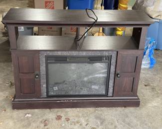 Dark brown wooden TV stand featuring an integrated electric fireplace insert with a faux stone surround, flanked by two storage cabinets, and topped with open shelving for media components.