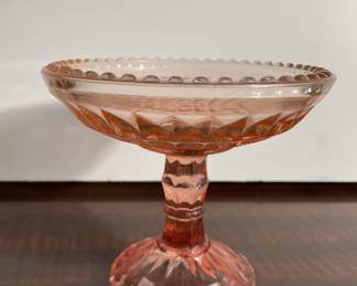 Pink Depression glass compote with raised geometric and beaded edge pattern.