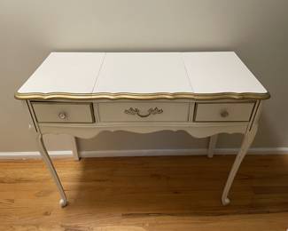 French Provincial vanity with flip-top mirror. Features elegant cabriole legs, gold trim, and crystal-style drawer pulls. Center section lifts to reveal a built-in mirror and storage compartment. Approx 40" x 17.5" x 31"