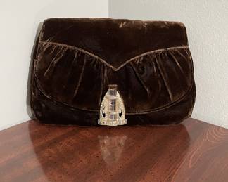 This charming vintage lot includes a luxurious dark brown art deco velvet clutch, paired with a collection of complementary accessories. The set features an ornate compact mirror with a tassel, a small satin coin purse with a delicate chain, and a soft velvet drawstring pouch. Please examine photos for condition.