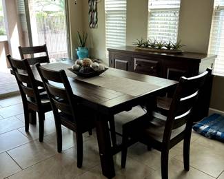 Kitchen table with a bench on one side and chairs on the other sides.