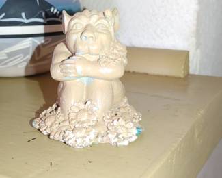 small statue of a gargoyle surrounded by daisies