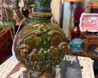 Mid century art deco Moon flask vase with green glaze and relief scene of people around a table 