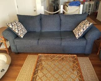 Nearly new navy sofa; rattan coffee table; area rug