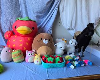 Squishmallows and other stuffed animals, with an American Girl horse in the back.