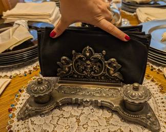 Gorgeous antique, cast-iron piece. Either a napkin holder (as it was used) with salt & pepper servers, or it's an inkwell 