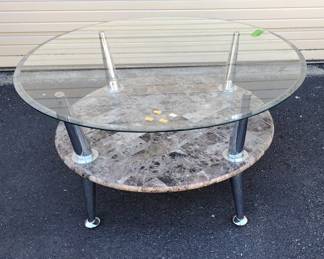 Two-tier round postmodern living room table with glass top and full marvel second tier. Opposing Chrome legs