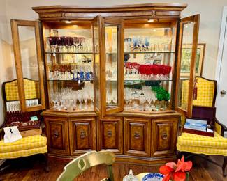 LARGE LIGHTED CHINA CABINET WITH AT LEAST 15 SETS OF STEMWARE. NOTICE THE TWO VINTAGE WINGBACK CHAIRS WITH MORE FLATWARE.