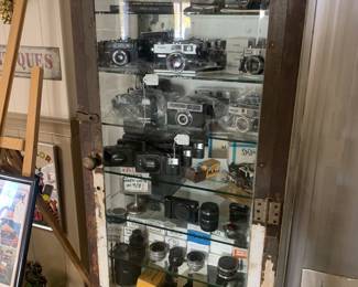 Antique metal cabinet with beveled glass sides, and glass shelves- from medical. Filled with cameras and accessories