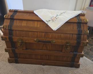 Vintage dome-top oak steamer trunk with brass hardware and leather straps — excellent condition.
