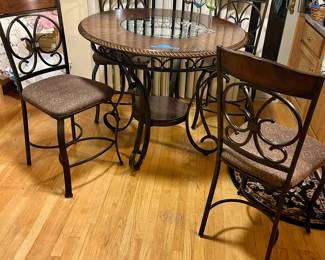 Dark wood round table with glass insert top
Four counter height with metal legs and upholstered seats