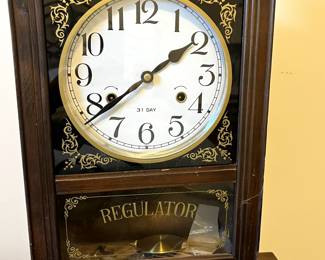 C102 - $40. Regulator Clock. Measures 12.5" wide x 5.25" deep x 19" tall. Has key and pendulum inside. Works!