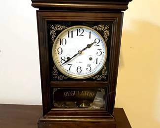 C102 - $40. Regulator Clock. Measures 12.5" wide x 5.25" deep x 19" tall. Has key and pendulum inside. Works!