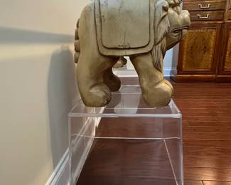 C42 - $450. Foo Dog Side Table. Glass top with lucite bases. Measures 66" x 15" deep x 28.5" tall. Dogs are porcelain material. 