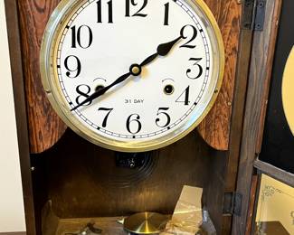 C102 - $40. Regulator Clock. Measures 12.5" wide x 5.25" deep x 19" tall. Has key and pendulum inside. Works!