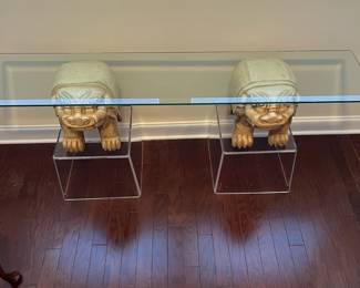 C42 - $450. Foo Dog Side Table. Glass top with lucite bases. Measures 66" x 15" deep x 28.5" tall. Dogs are porcelain material. 