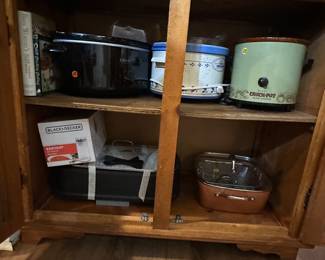 Bottom of the handmade cabinet
3-4 crockpots available; crockpot cookbooks are here too
New can opener
Grill 
Copper pan and attachments 