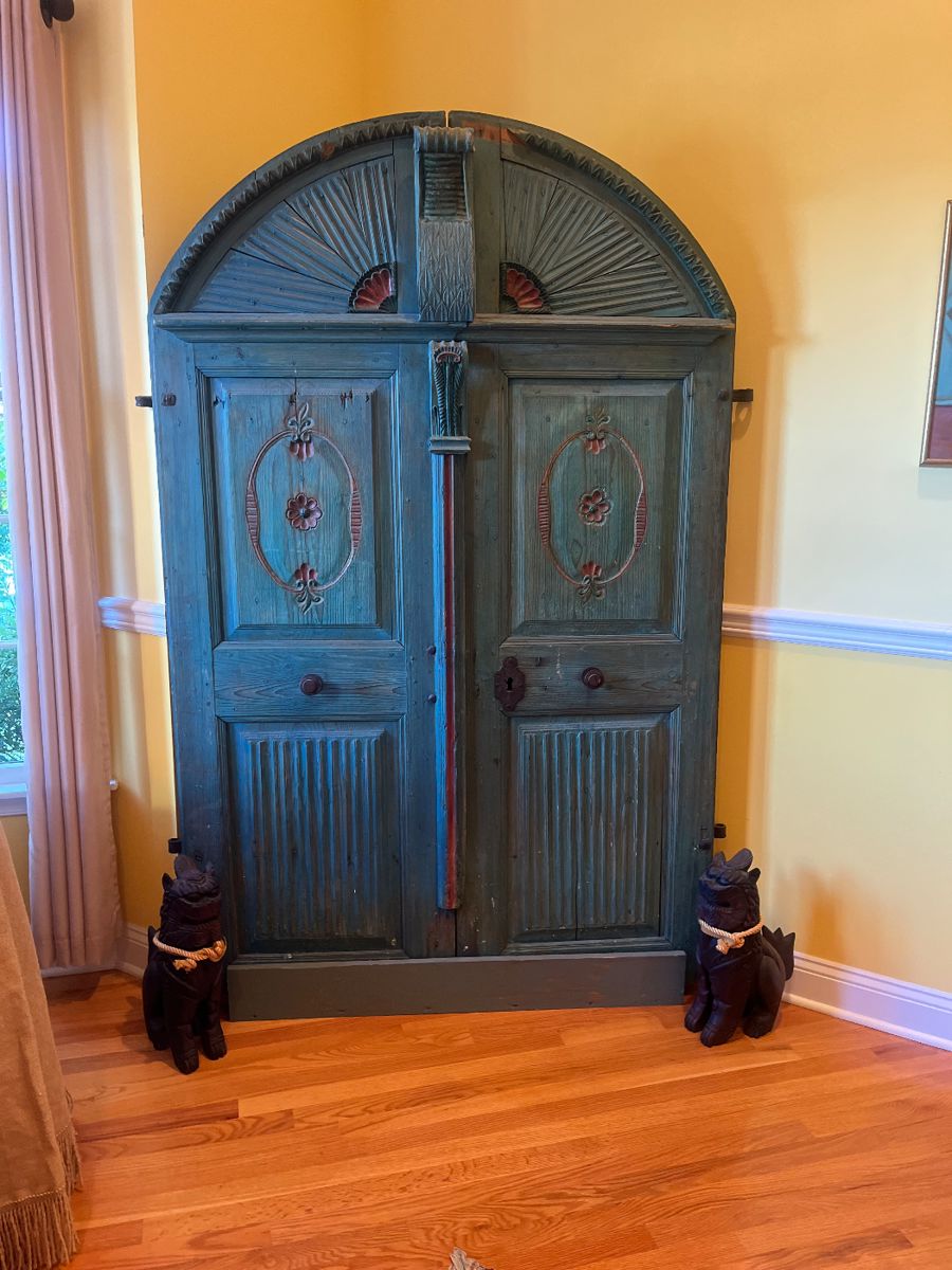 Antique painted arched doors protected by wood carved foo dogs .