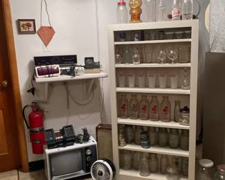 Electronics and bottles and jars, white shelf