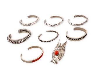 3393
A group of Southwest sterling silver and set coral jewelry
Mid/late 20th century
Eight works:

Steven Pooyouma (b. 20th century, Hopi Pueblo)
A Hopi sterling silver narrow cuff, late 20th century
Stamped with artist's cipher
A small cuff with sawtooth overlay design and shadowbox accents
6.125" inner C x 0.375: H, with a 1" gap

A group of Southwest sterling silver and set coral jewelry
One illegibly marked for maker; one marked for sterling
Comprising three chunky incised and stamped narrow cuffs, as well as two twisted wire cuffs, a coral inlay cuff, and a large set coral eagle motif ring
7 pieces
Largest cuff: 6.5" inner C x 0.25" H; smallest: 5.5" inner C x 0.125" H; Ring size: 5.25; 2.25" H

8 pieces total
190.5 grams gross
Estimate: $700 - $900