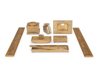3081
A Tiffany Studios gilt-brass and slag glass 'Pine Needle' desk set
Early 20th century
Each marked: Tiffany Studios / New York; and variously numbered
Comprising an inkwell with glass well, a small scale, a blotter, a utility box, a letter opener, a pen tray, a picture frame with easel back, and a two-piece calendar frame
9 pieces
Inkwell: 3.625" H x 4.25" W x 4.25" D; Each calendar frame: 19.125" L; Frame aperture: 2.125" H x 3.25" W
Estimate: $900 - $1,200