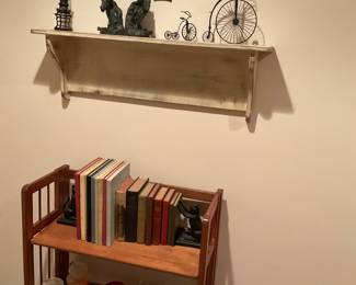 Bookshelf with 2 cast iron cat bookends, AHS yearbooks, old hard backs books. Candles, melting tarts. Top shelf has black horse bookends, bicycles, tree of life,