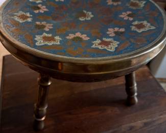 Vintage enameled brass foot stool with floral motifs and three legs.