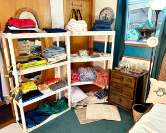 various clothing, linens, blankets, nightstand, floor lamp