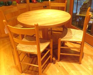 Beechwood round pedestal table with four rush seat chairs.