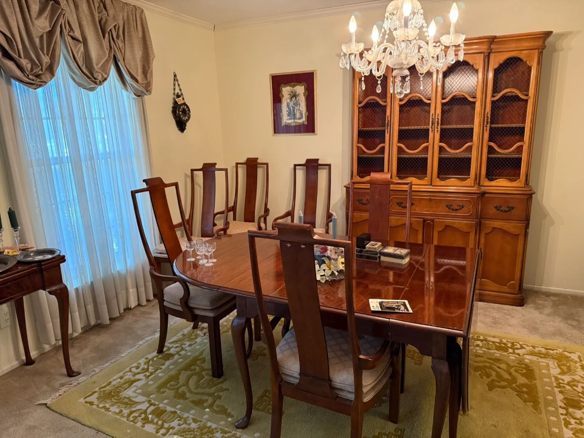 Elegant wood dining table with six high-back chairs and matching China cabinet. Beautiful craftsmanship, ideal for traditional dining spaces.