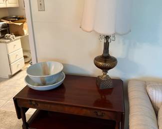 Vintage two-tier mahogany side table with brass hardware, Ceramic bowl sets and an ornate brass-based lamp with crystal accents.