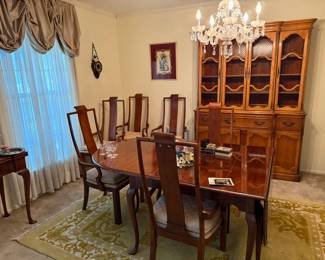 Elegant wood dining table with six high-back chairs and matching China cabinet. Beautiful craftsmanship, ideal for traditional dining spaces.