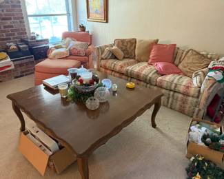 Comfortable floral sofa with coordinating coral armchair and ottoman. Solid large wood scalloped-edge coffee table.
