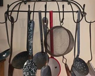 Various vintage enamelware spoons and other cooking utensils on wire wall rack