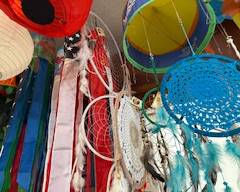Colorful mix of hanging décor including paper lanterns, patriotic windsocks, and handcrafted dreamcatchers with feathers and lace. Bright display for indoor or outdoor decoration.