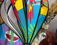 Colorful hot-air-balloon style hanging spinner featuring bright parrots and tropical artwork. Vibrant outdoor décor perfect for porch, patio, or garden.